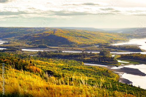 View from the hill to the river down in the valley surrounded with forests with yellow and green autumn foliage. Sagitawa lookout, Peace River, Alberta, Canada.