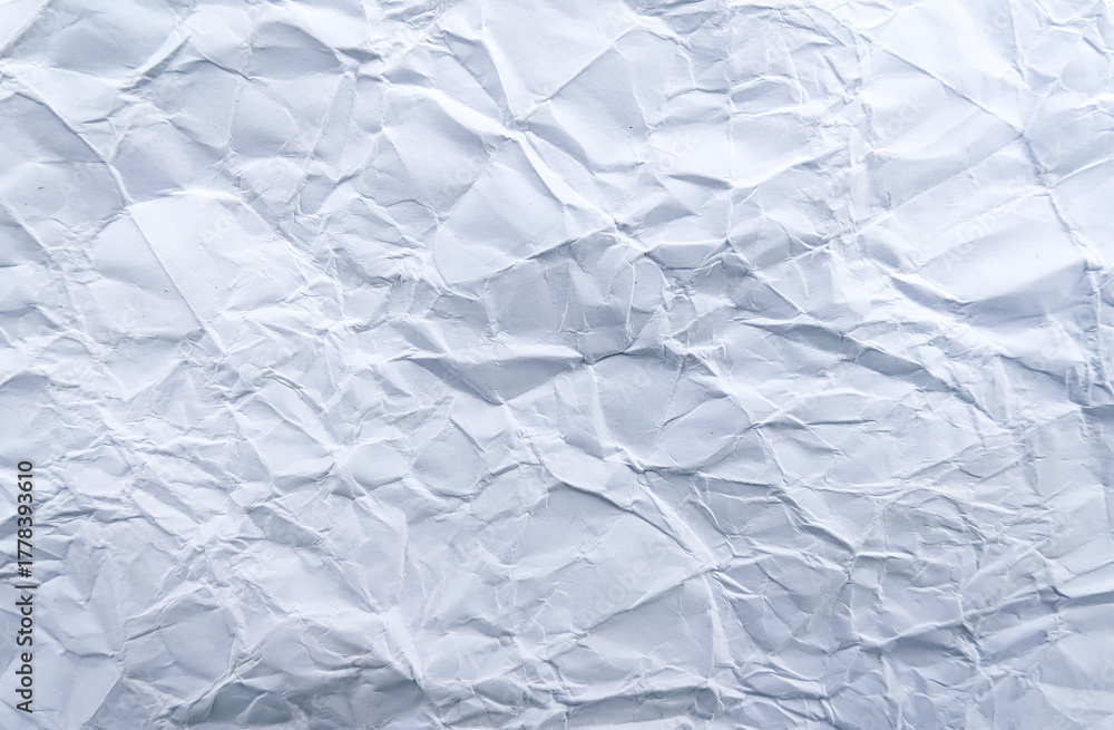 Obraz premium Wrinkled white paper surface under natural light, showing real folds and texture. Ideal for background, design, or minimal creative projects.