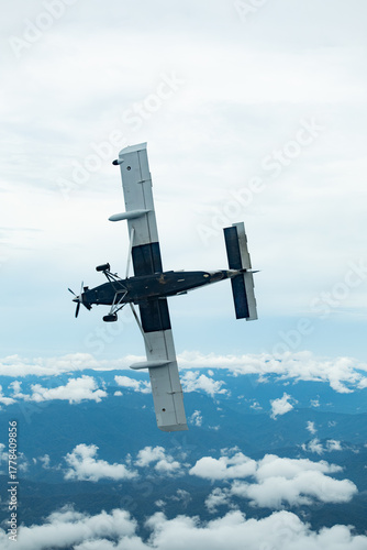 A utility turboprop aircraft captured mid-bank against a cloudy sky