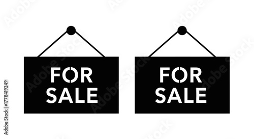 Two black signs displaying the words for sale hanging from strings
