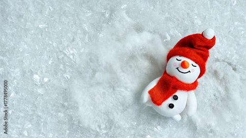 Video background with a cheerful mood a snowman lies in the snow and makes a snow angel waving arms. Clean icy texture from top view with copy space. Loop