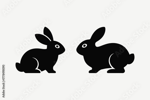 Two black silhouette rabbits facing each other on a light background