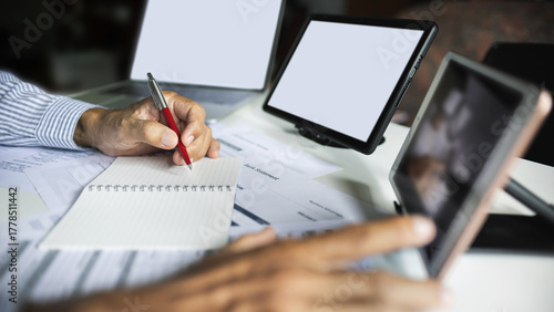 close up shot, hand of businessman working and meeting online with digital tablet checking business contract, various documents and taking note working at home to start e-commerce business