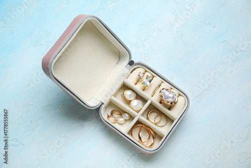 Bild auf Leinwand Open organizer with different golden jewelry on light blue background