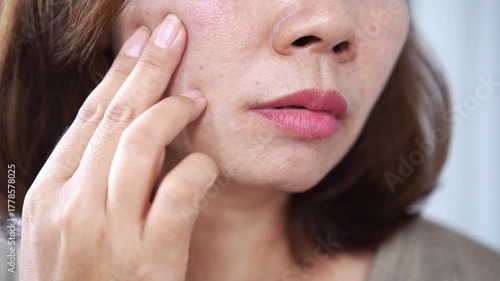 woman in middle age with visible pores, smile lines, dark spots, and skin damage on her face. Concept of natural aging, skincare awareness, wrinkles, and mature skin health