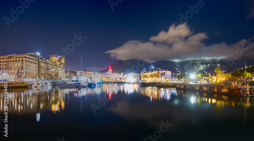 Table Mountain under the clouds is reflected in the still waters of a marina for luxury motor yachts in Cape Town, South Africa