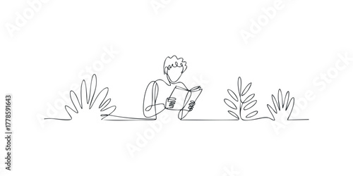 Person reading book outdoors surrounded by foliage