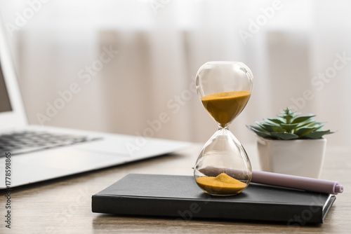 Hourglass with laptop, note...