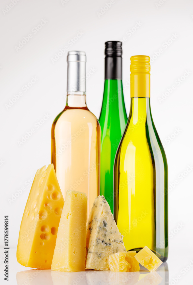 Fototapeta premium Assorted cheeses and wine bottles on white background
