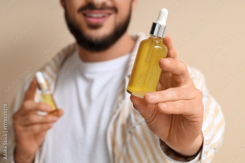 Fototapeta premium Man holding dropper bottle with natural skincare serum, organic cosmetic product for healthy skin and hair care