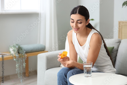 Young woman taking vitamin ...