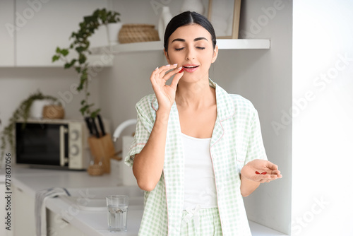 Young woman taking vitamin ...
