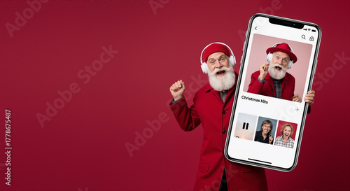 Man dressed as Santa Claus holding smartphone displaying Christmas music playlist. Festive holiday streaming app interface with artist thumbnails and headphones. Digital entertainment for winter