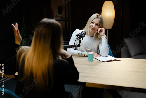Two female podcasters recording a new episode in a professional studio