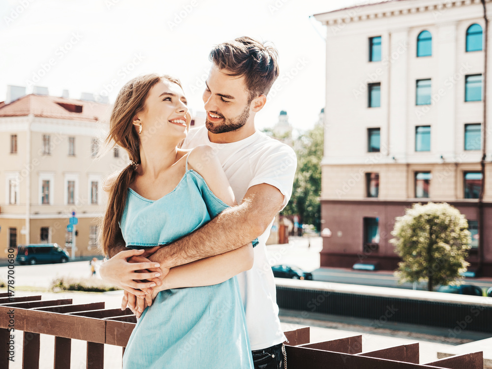 Obraz premium Portrait of smiling beautiful woman and her handsome boyfriend. Woman in casual summer jeans dress. Happy cheerful family. Female having fun. Couple posing on the street background