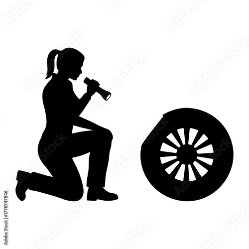 Person examining wheel with flashlight silhouette kneeling