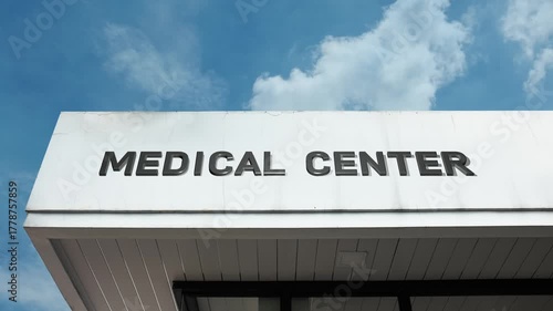 A medical center word sign prominently displayed on a hospital building under a clear blue sky, symbolizing healthcare, patient care, treatment, and wellness services