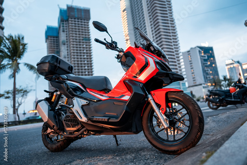 red aggressive motorbike or maxi scooter parked in big modern city