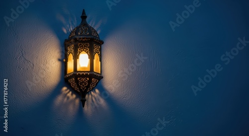Ornate moroccan lantern casting soft glow on blue wall