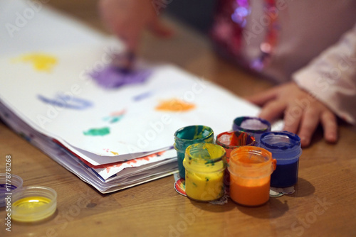 Child finger painting with bright colorful paints on paper during an art lesson or home activity. Early childhood creativity, fine motor skills, and the learning through play concept.