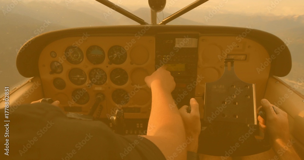 Obraz premium Pilot and co-pilot adjusting panel controls during sunset flight, with radio stack and yoke