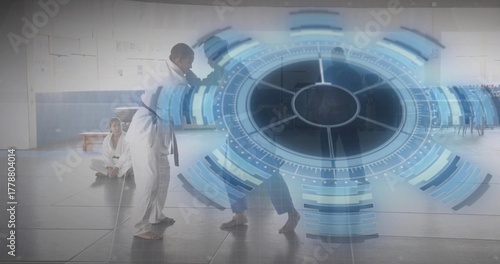 Sparring fighters in uniforms and colored belts engaging strikes in dojo, with digital HUD overlay