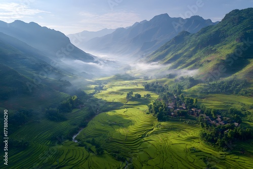 High‑resolution aerial view of a misty mountain valley with soft floating fog drifting between evergreen ridges and dawn light illuminating the rugged peaks rice terraces in the morning