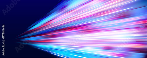 Dynamic light trails streak across the night cityscape in bright neon colors. Motion blur enhances the sensation of speed. Vibrant glow emphasizes modern urban energy.