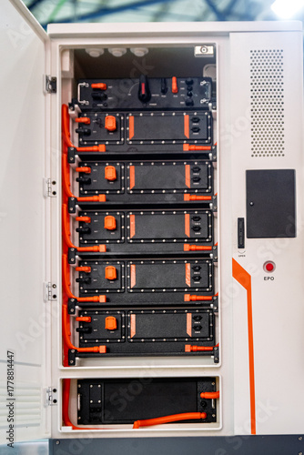 Close-up of a modern modular battery energy storage system with black battery packs and orange cables inside an industrial cabinet. Represents sustainable power technology.