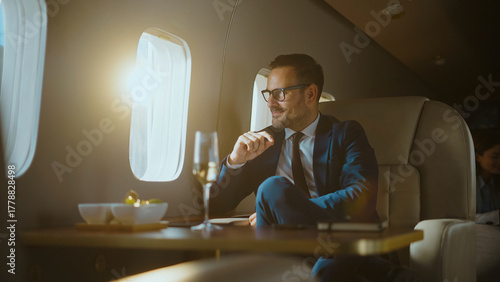 Billede på lærred Successful businessman traveling in a private plane, sitting by the window with