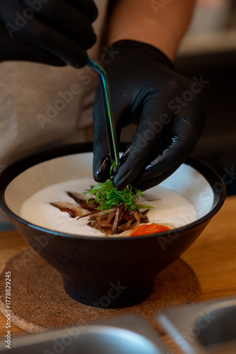 Ramen noodle in intense broth with Chashu pork, fresh green onions and egg in bowl.