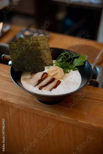 Ramen noodle in intense broth with Chashu pork, green vegetables and scallop in bowl.