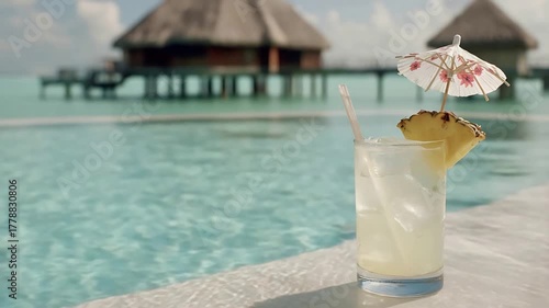 Refreshing Tropical Cocktail by Infinity Pool Overlooking Luxurious Overwater Bungalows in Paradise.