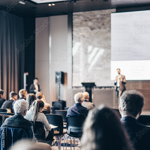 Speaker giving a talk in conference hall at business event. Rear view of unrecognizable people in audience at the conference hall. Business and entrepreneurship concept