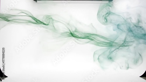 Abstract studio shot with green/blue flowing dye patterns on white background