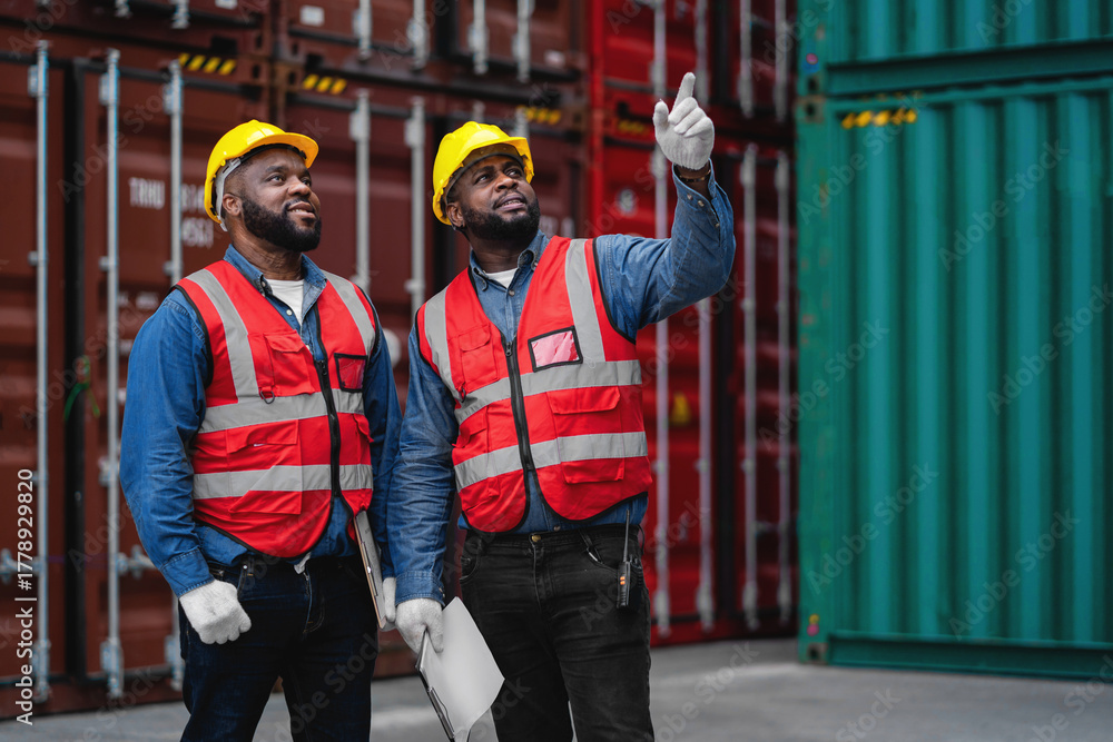 Obraz premium Two men wearing safety gear and pointing at a laptop