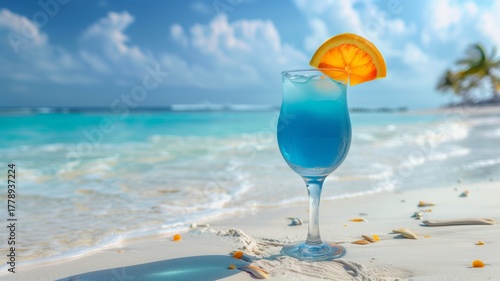 Blue tropical cocktail with orange slice on sandy beach and turquoise sea