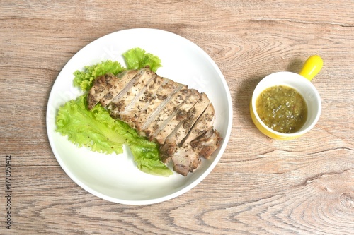 grilled slice salty pork loin with black pepper topping lettuce on plate dipping spicy hili sauce cup
