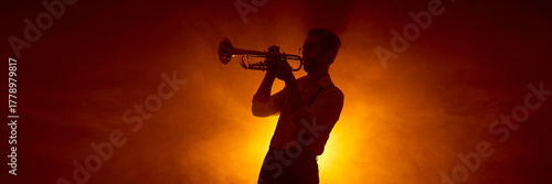 Canvas Print Trumpet player silhouette against warm concert lighting background