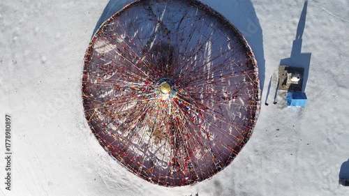 Aerial view of the Buddhist stupa covered in snow, surrounded by prayer flags, creating a stark contrast against the white landscape, Litang, China.