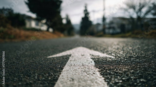 low angle of white arrow on asphalt road showing goal