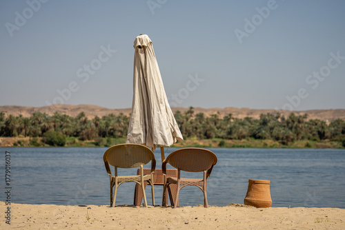 Chairs and parasol on sandy beach by the Nile River, Aswan, Egypt
