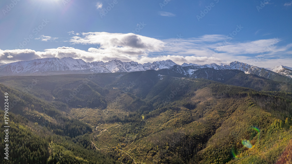 Naklejka premium Sunlit Tatra Mountains Above Forested Valley, Early Snow on Peaks, Zakopane Region, Poland – Aerial Drone View