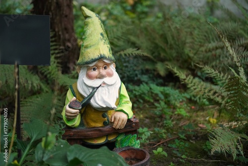 Vintage figurine of a garden gnome among fern thickets in autumn in the botanical garden while traveling in Europe