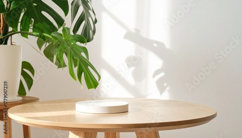 Minimalist interior with round wooden table, white dish, and monstera plant casting shadows