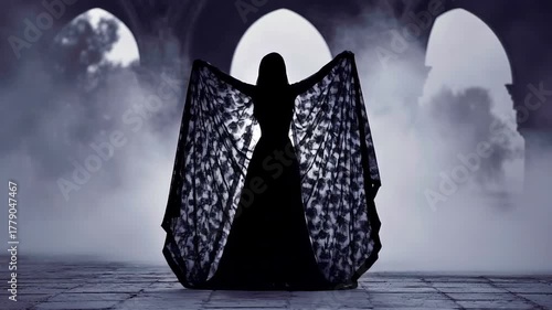 Silhouette of cloaked figure in misty gothic setting