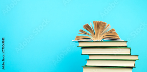 Open book, hardback books on wooden table, on a blue background. Back to school. Copy space for text. Education background. panorama, banner.