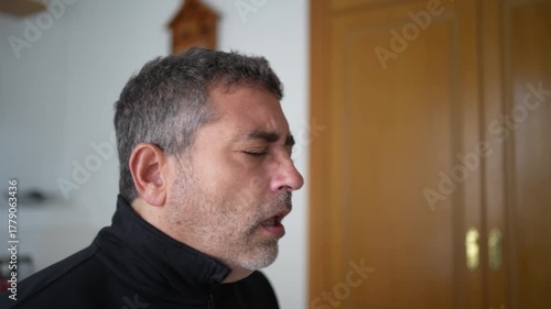 A Man Who Is Experiencing Sneezing and Coughing Symptoms While Indoors in His Home