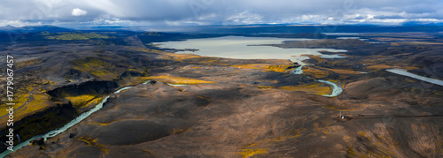 Принти на полотні Aerial view of Iceland volcanic highlands shows a braided turquoise glacial river across dark lava toward a milky blue lake near Sigoldugljufur or Landmannalaugar in soft daylight