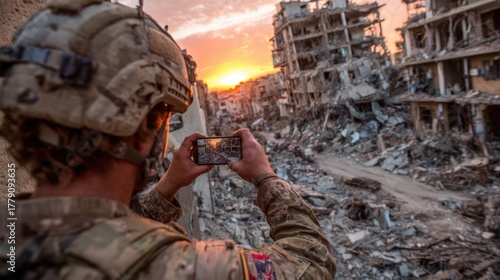 Soldier photographs a war-torn city at sunset. Rubble and destruction dominate the scene